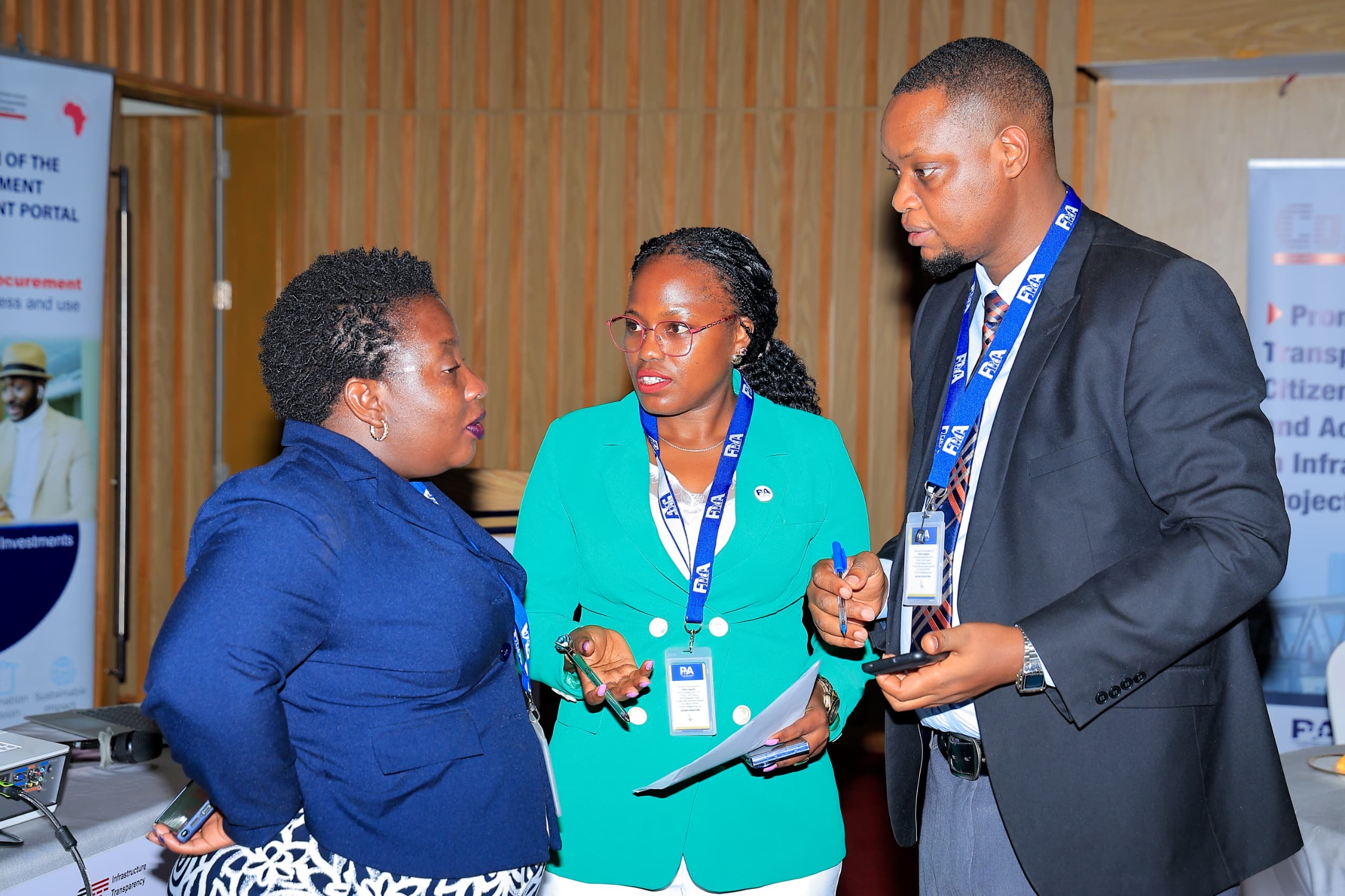 Three people continue a candid conversation beside a portal banner after the GPP relaunch event.